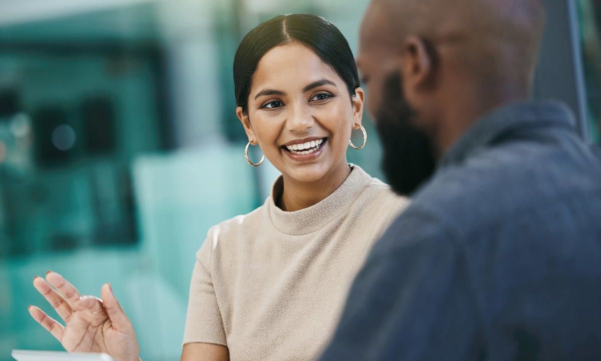 professional woman with laptop talking to male coaching client