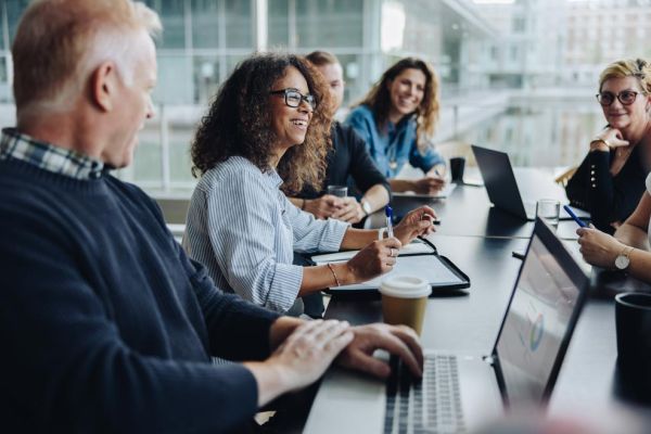 group of coworkers in conference room having team discussion with laptops
